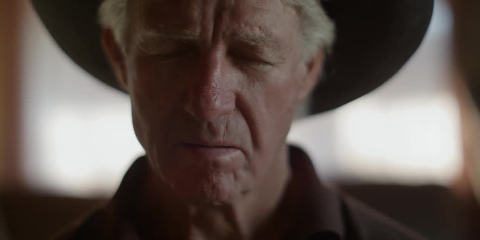 An elderly man wears a cowboy hat