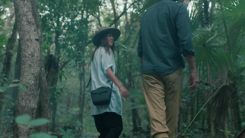 A man and woman walk together in the green forest