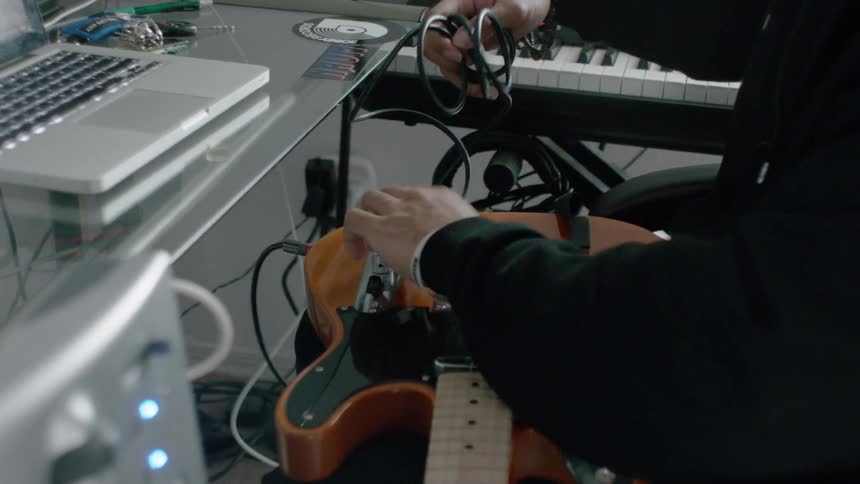 A man plugs his guitar into an amp