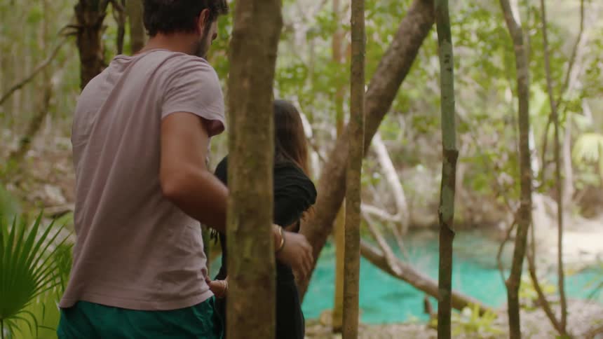 Man and woman hold hands as they walk around the trees