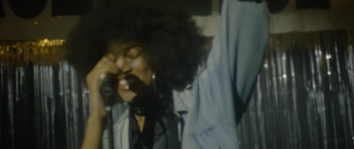 A woman sings into a microphone on stage