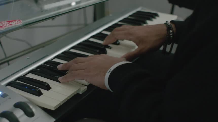 A man plays a small keyboard at a desk