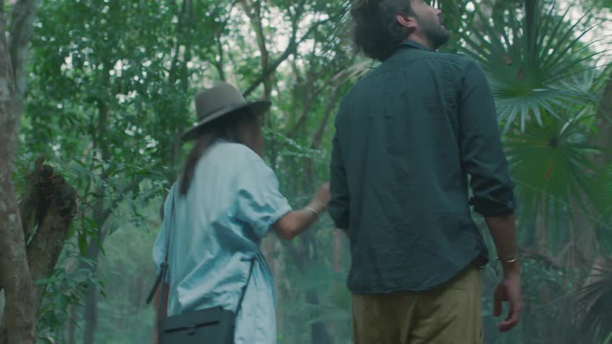 A man and woman are walking through the forest together