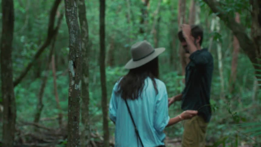 A man and woman flirt while hiking in a jungle