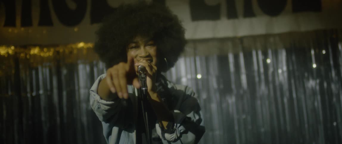 An african american woman is pointing as she sings on a stage