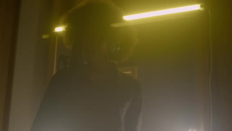 A woman sings into a microphone in a dark room