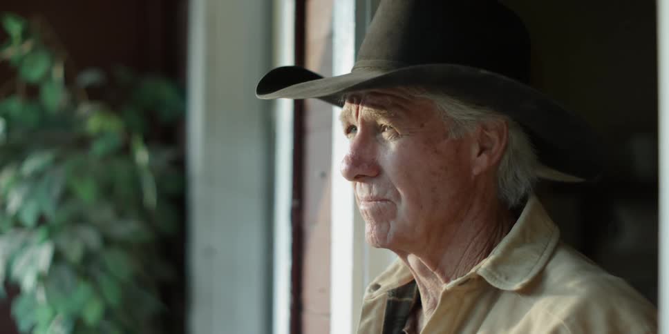 An older man is standing in a doorway staring during the day