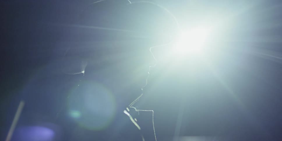 A cowboy stands in a paddock at night