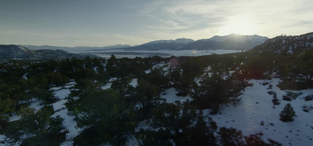 The sun is coming up over a mountain during winter