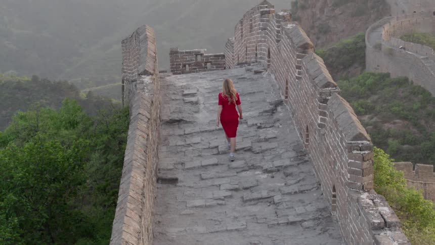 A woman walks over the stone wall on the hill