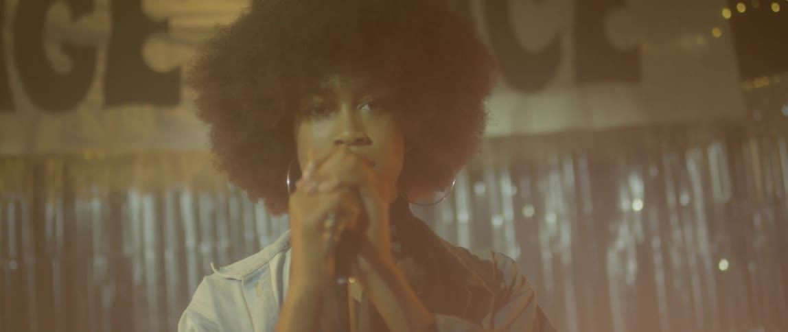 Woman standing on a stage holding a microphone close to her face