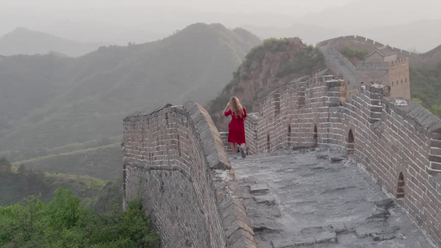 Woman walks on a large wall in the mountains