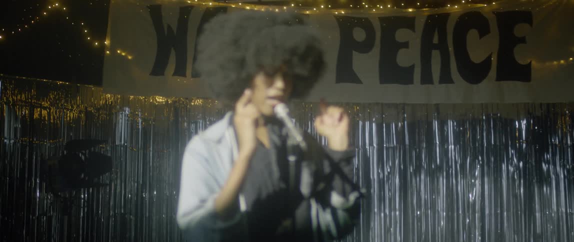 A woman sings into a microphone on stage