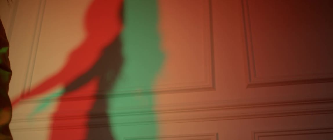 A woman is casting a shadow on a wall as she dances in a room