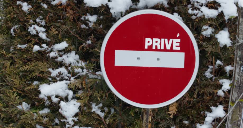 Snow falls on a sign marking a private way