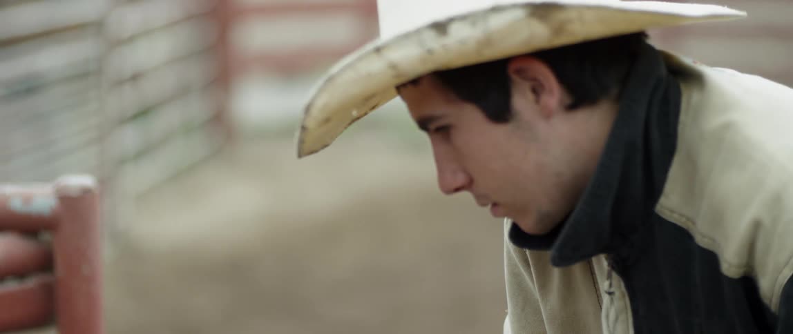A cowboy stands on a ranch