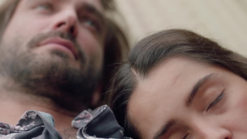 A man and woman cuddle in a hammock