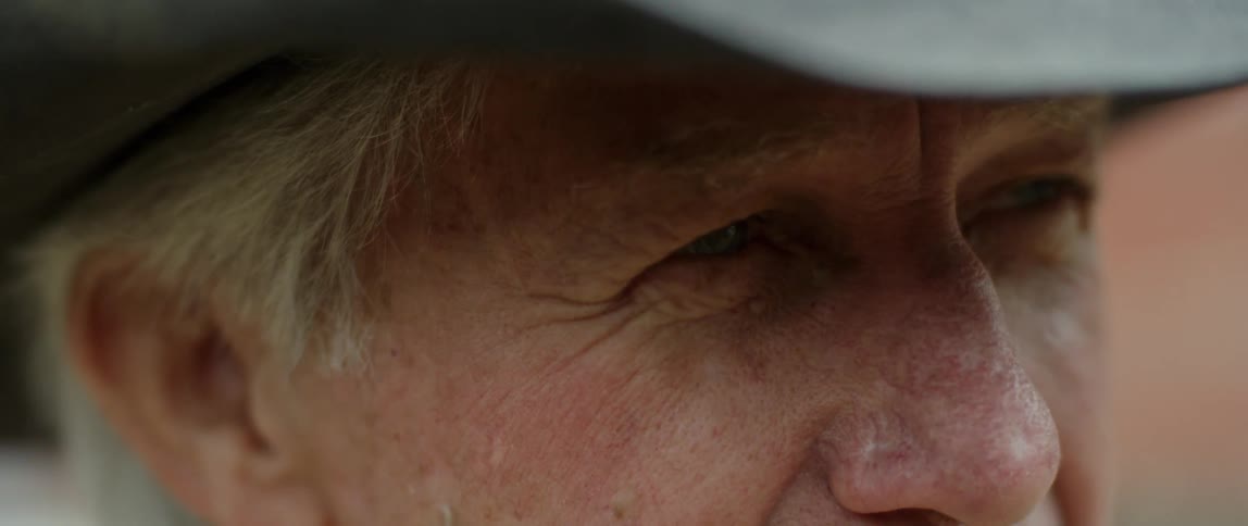A man in a cowboy hat squints as he stares