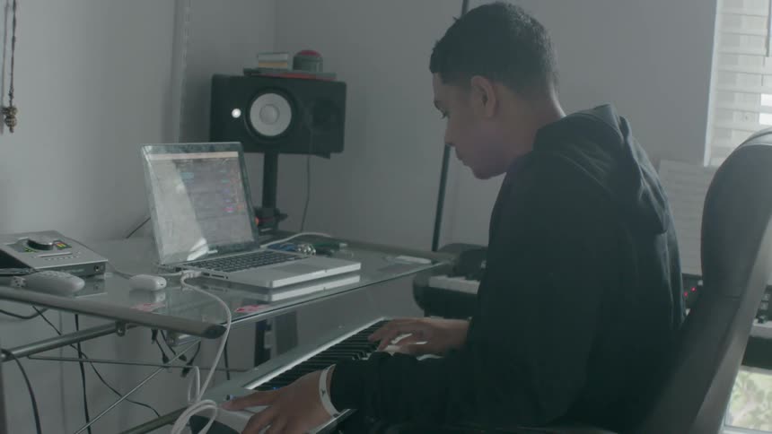 A man nods his head as he plays music on a keyboard