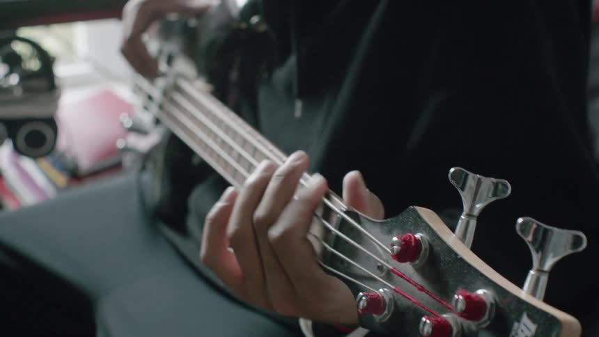 A person sitting down plays the guitar