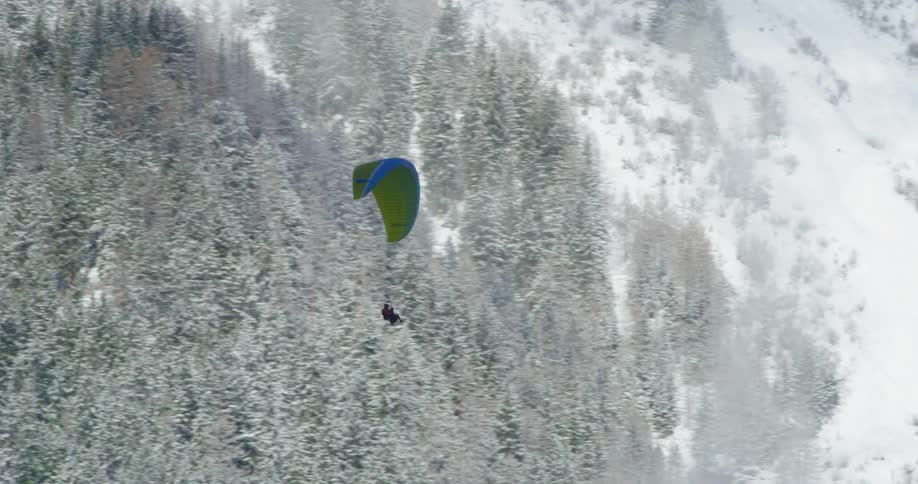 A man is parasailing past the mountain