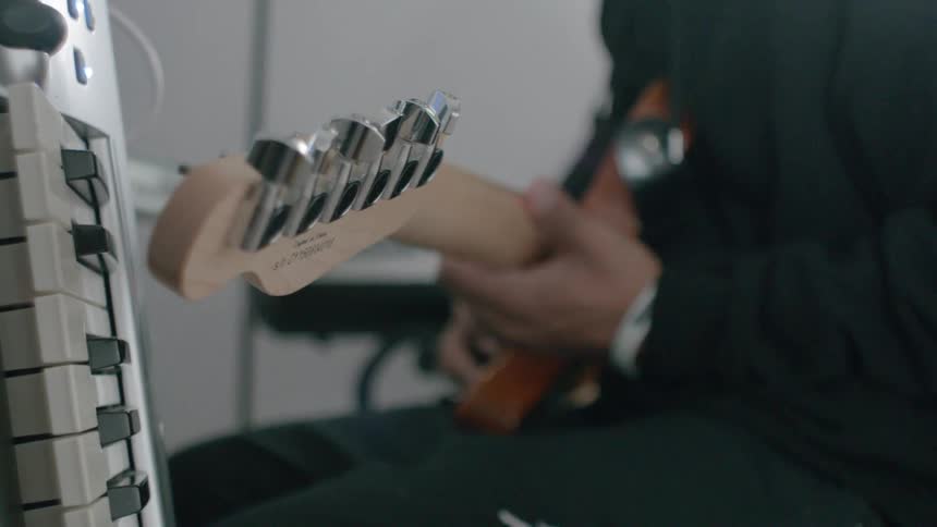 A man plays an electric guitar in a studio room