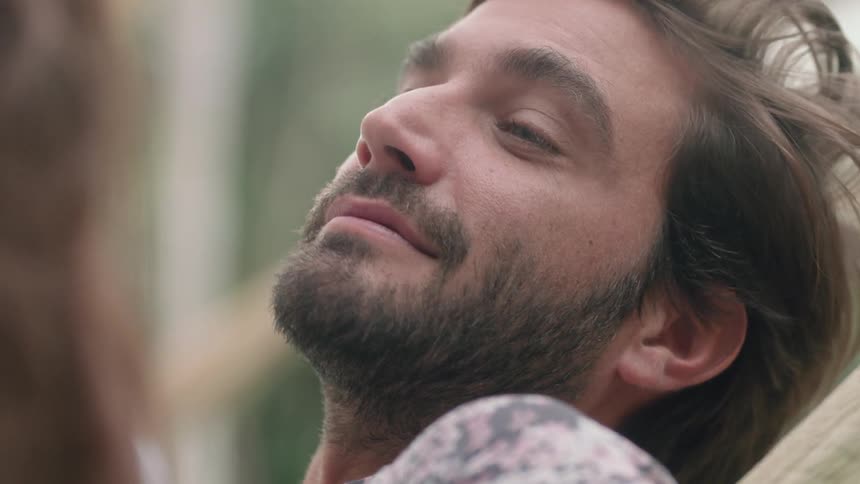 A man looks up and then down to the person next to him as he smiles