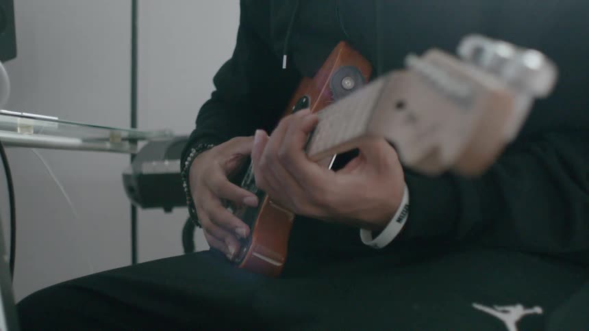 A person is sitting down playing a guitar