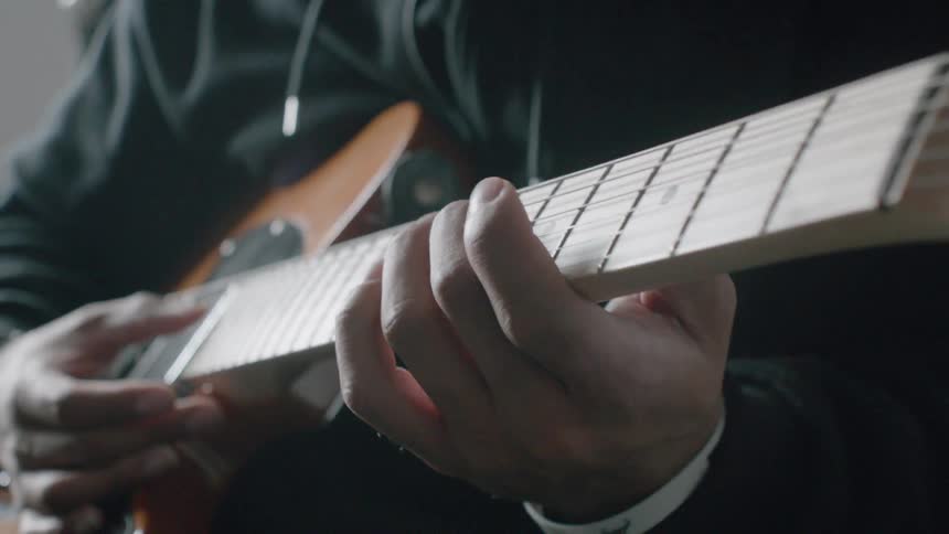 A man is playing a guitar inside during the day