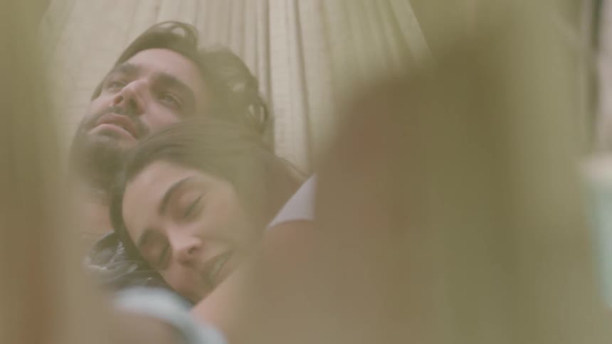 A man and woman lay in a hammock together