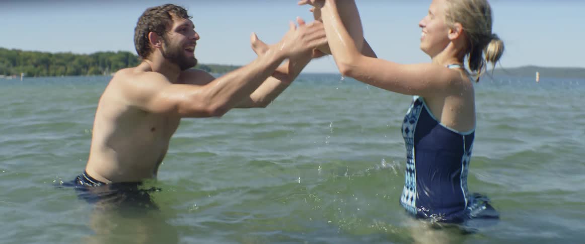 A couple plays with their baby son in the water on a sunny day