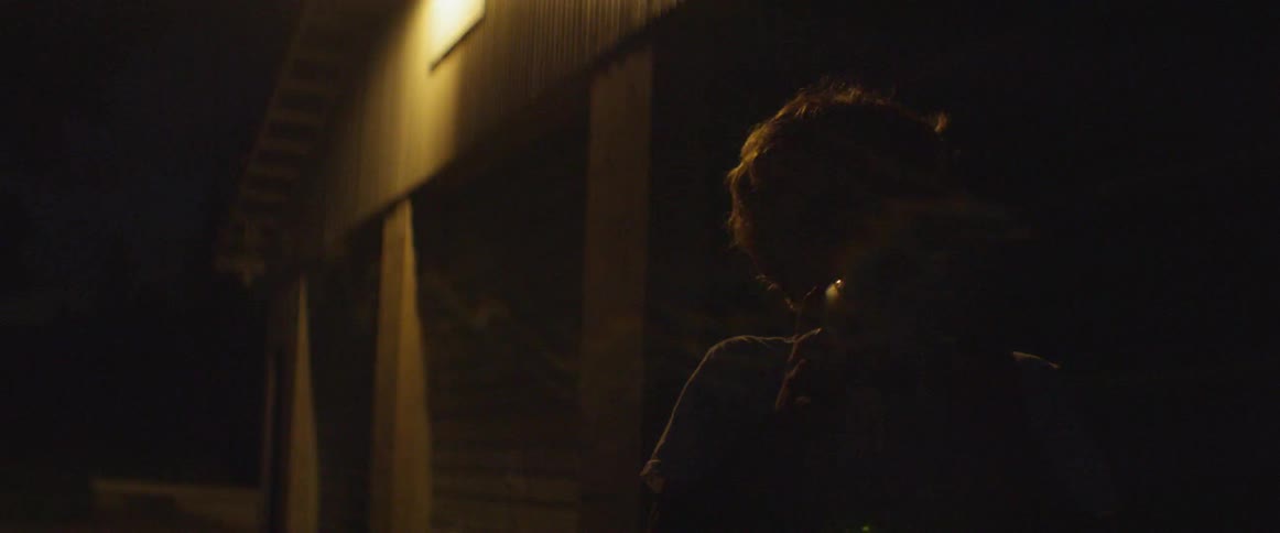 A kid is looking at a jar full of lightning bugs at night