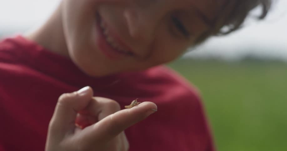 Young boy looks at an insect on his finger