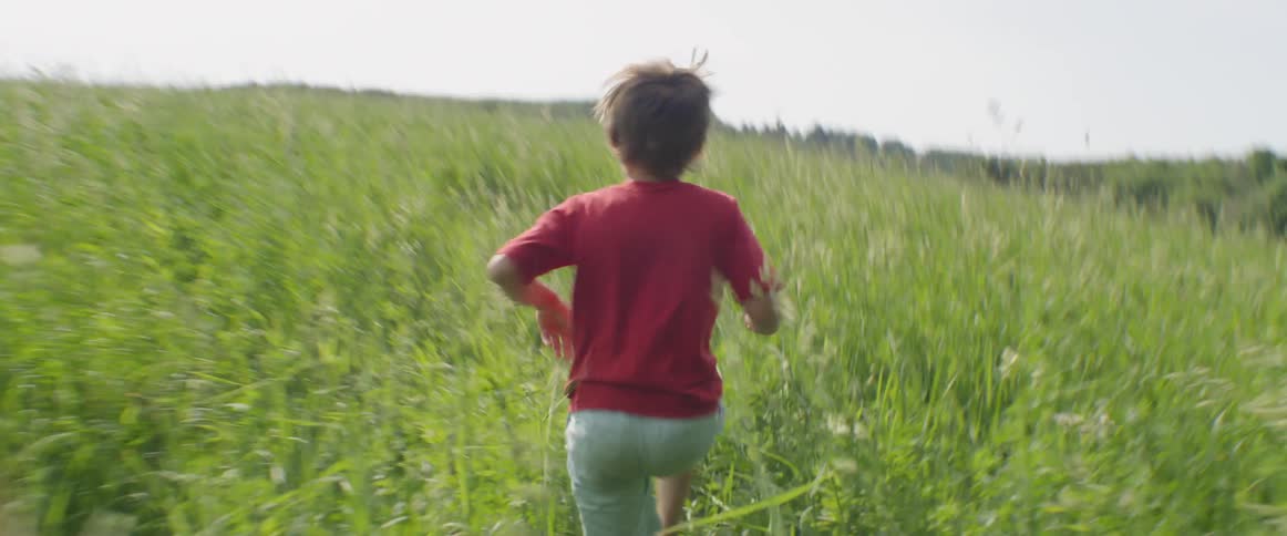 A child runs fast into the tall grass
