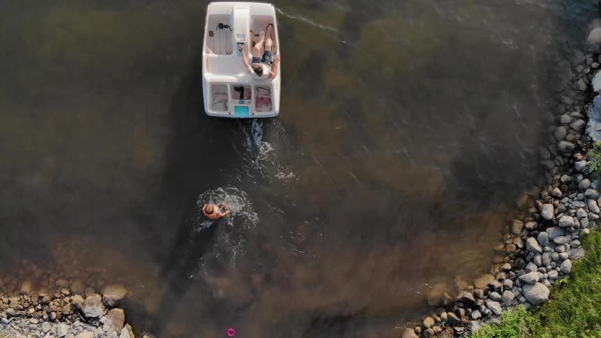 A person chases after a small boat as it is pedaled away