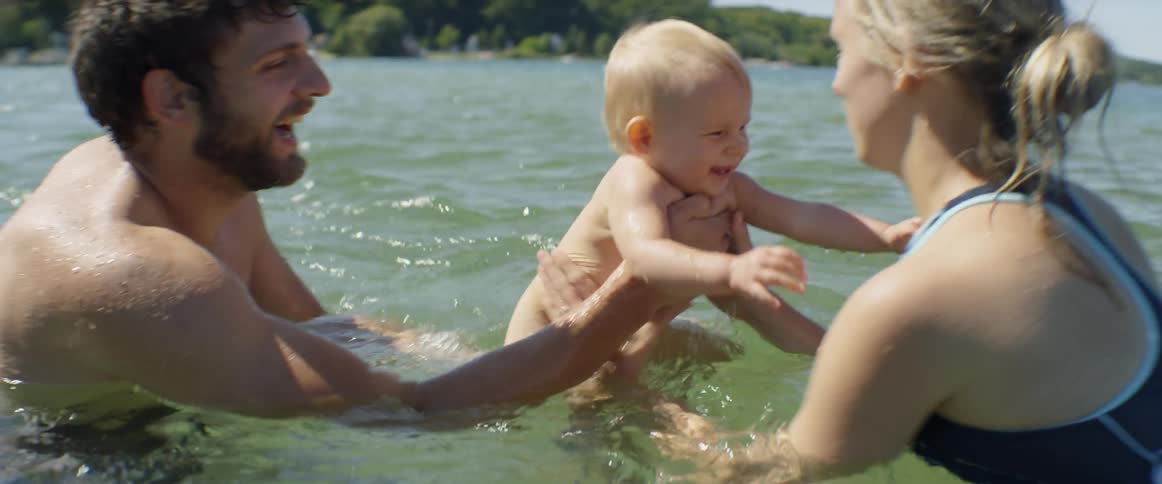 Parents play with their baby in the lake