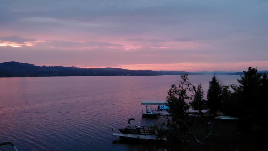 The sun is setting near this pier by the lake