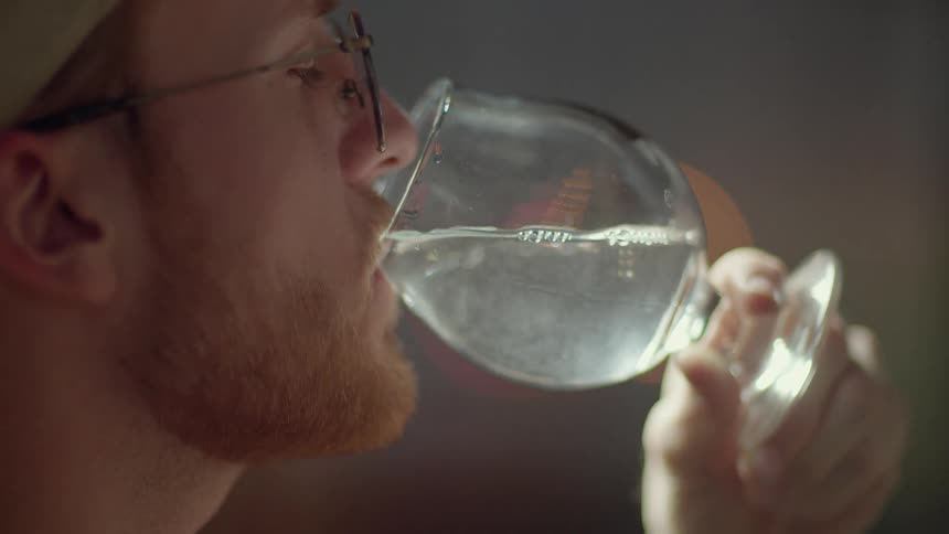 A man is taking a drink from a beverage