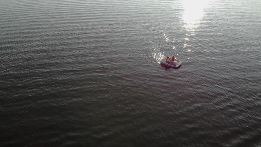 Two people paddle a paddle boat in the lake on a sunny day