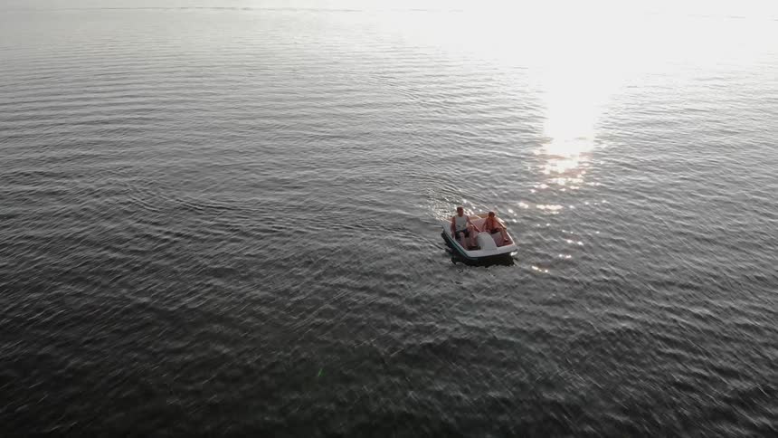 Two people are pedaling a boat on a body of water during the day