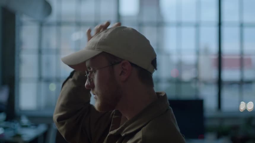 A man adjusts his baseball cap and scratches his head