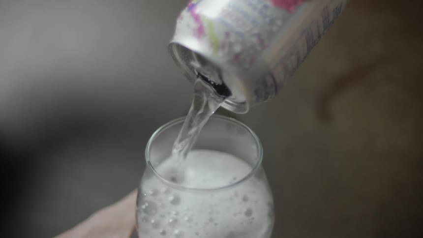 Soda being poured from a can into a glass