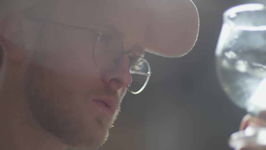 Man wearing glasses and a hat concentrates while looking to the side