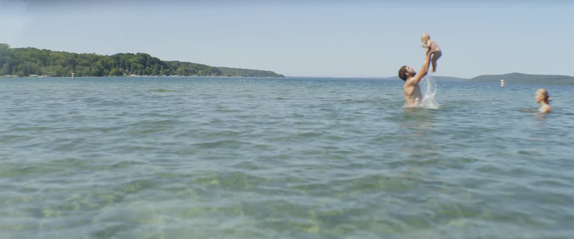 A man swims with a baby in a lake