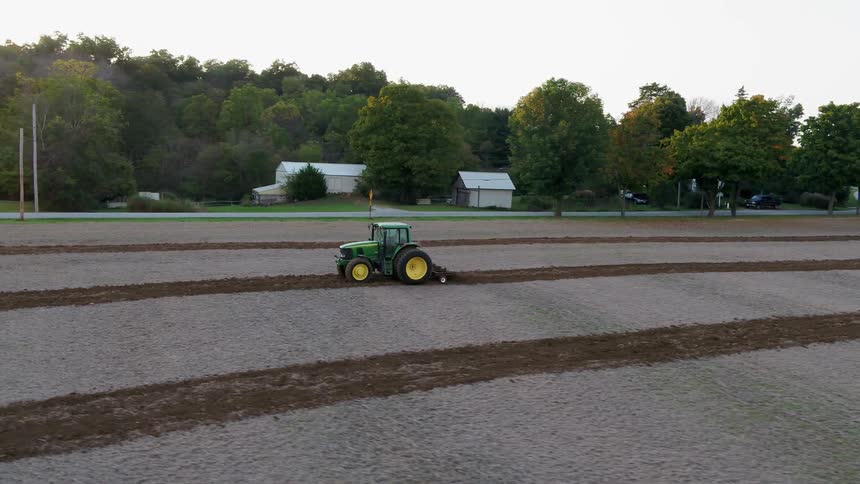 The tractor is slowly working the large farm