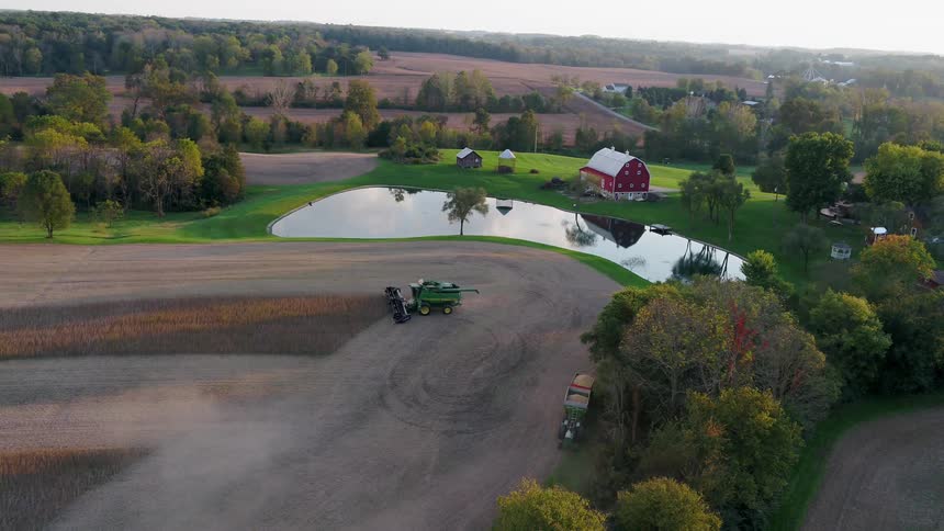 The tractor is working the fields by the pond