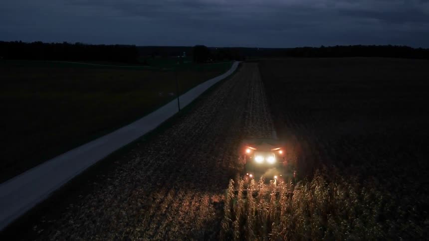 The tractor is working at night with flashing lights