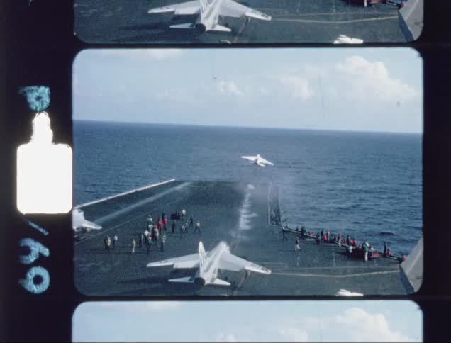A fighter jet is taking off from a carrier deck in the ocean in daylight
