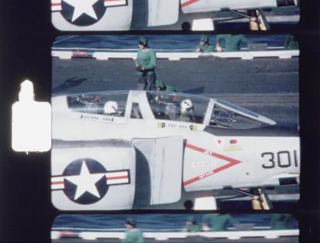 A navy jet is waiting to take off on a carrier deck during the day