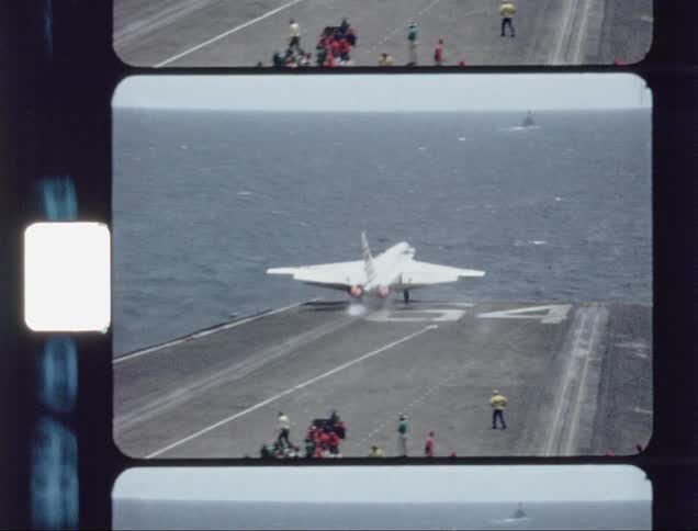 A jet slowly takes off from the ocean hangar as people watch on